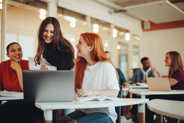 Un étudiant échange avec son professeur dans une salle de classe, favorisant un apprentissage actif et des discussions enrichissantes sur des sujets d'actualité liés à leur formation.